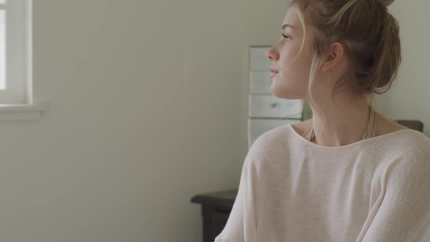 A white woman focuses on an activity while sitting in bed