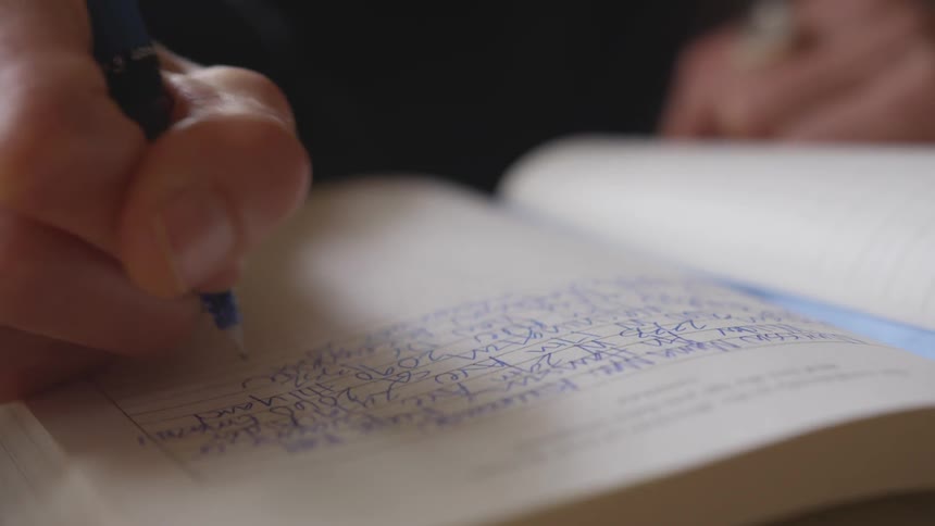 A woman writes in a journal with a pen