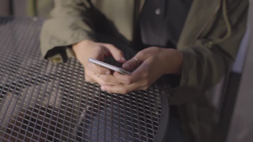 A person is typing on their phone and sitting down