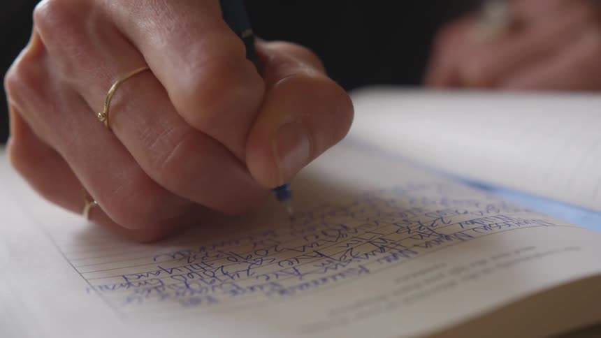 Woman writing in a journal while sitting in a coffee shop