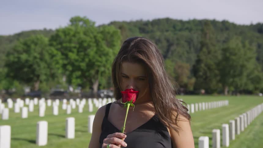Woman smelling a rose on a cemetery
