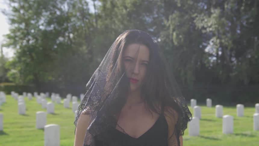 A woman wears a black veil at the cemetery