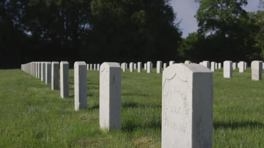 White headstones stand in rows in a cemetery