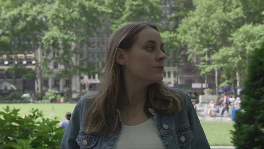 A woman looks around while sitting in a park