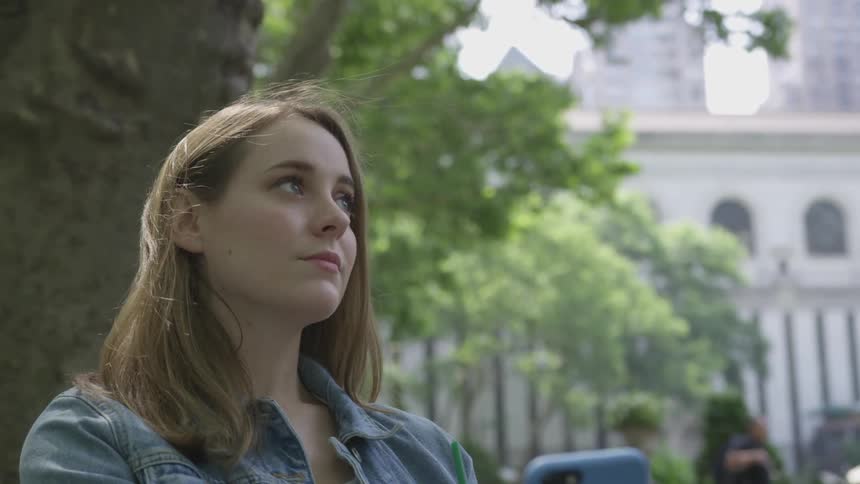 A woman is sitting outside with her cellphone