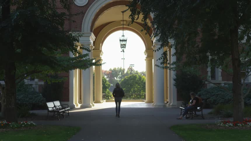 A woman walks across a university campus path