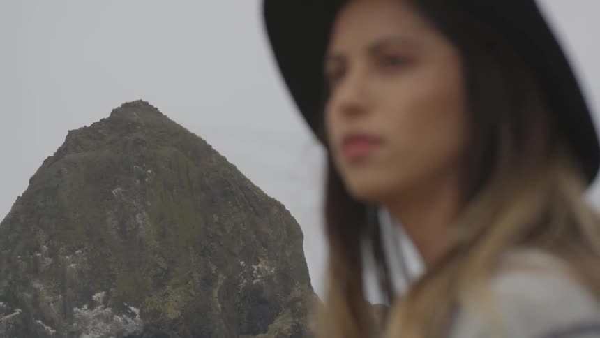 Woman stares intently as she is near a large rock