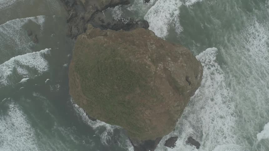 Waves crash around uninhabited rocky island in ocean
