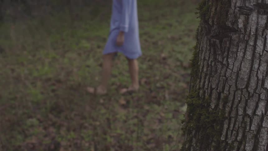 A woman walking barefoot through a forest