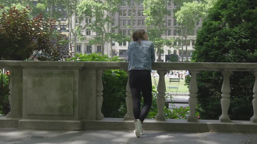 A person stands at a railing looking out at the city