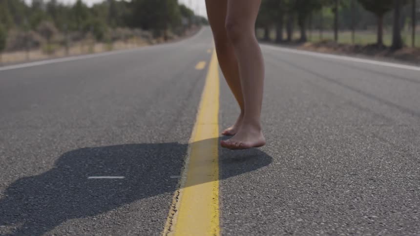 Woman running down a road barefoot