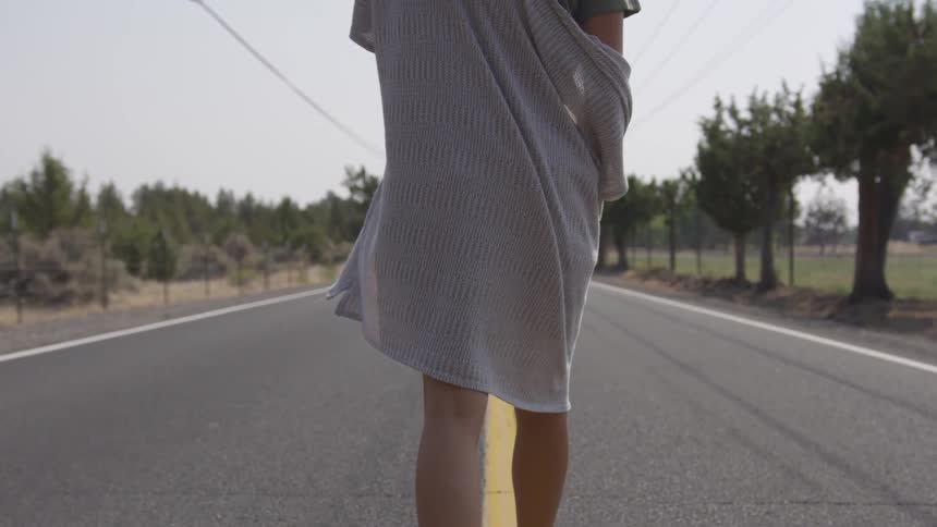 A woman in a light dress walking down a road