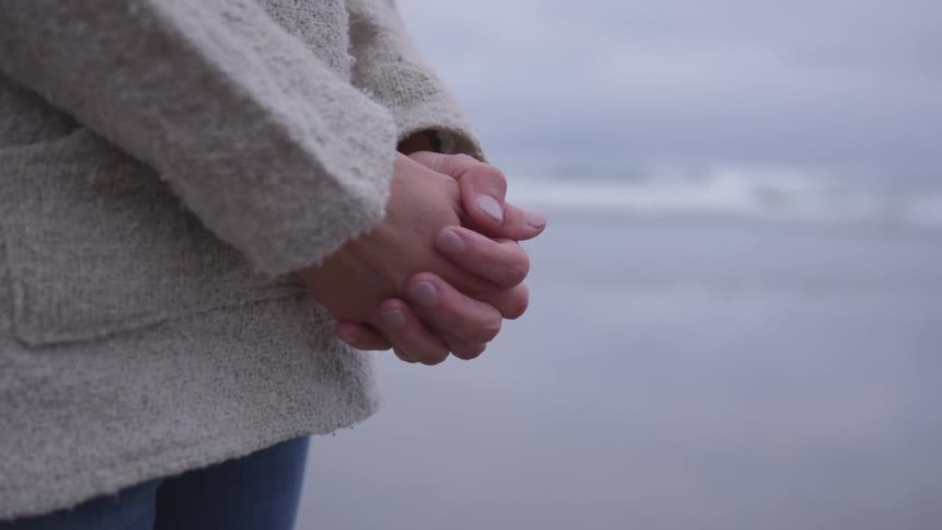 Woman's folded hands in front of her while standing outside