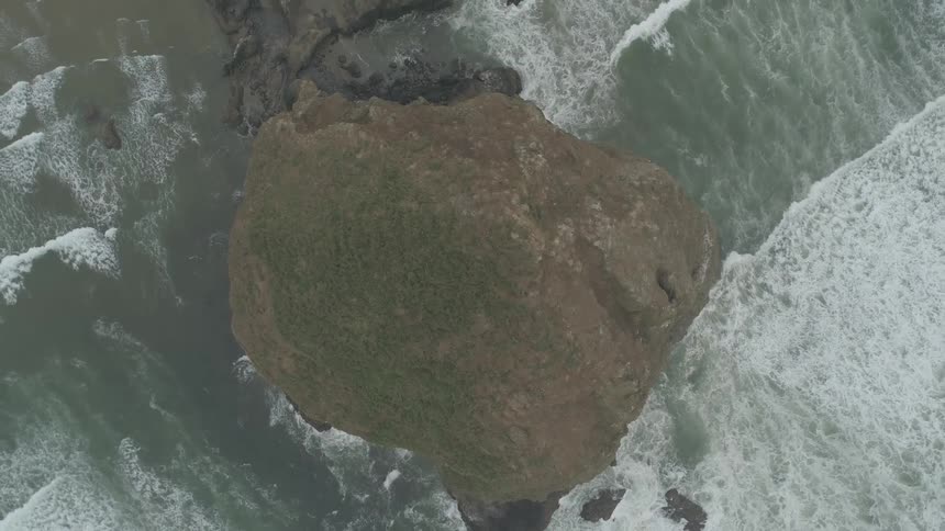 The waves clash against the rock formation by the shore