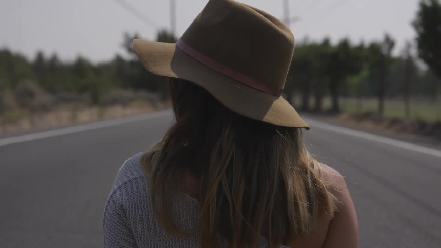 A woman wearing a sun hat standing in the middle of the street