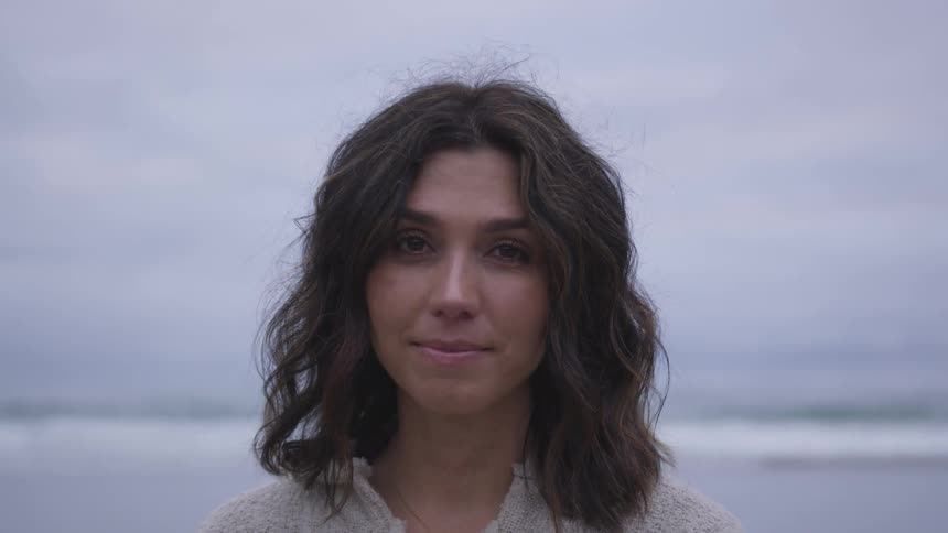 A brunette white woman turns her head and stares while slightly smiling