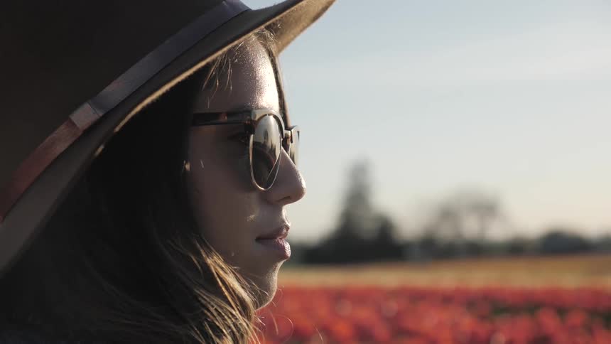 A woman is outdoors wearing a hat and sunglasses