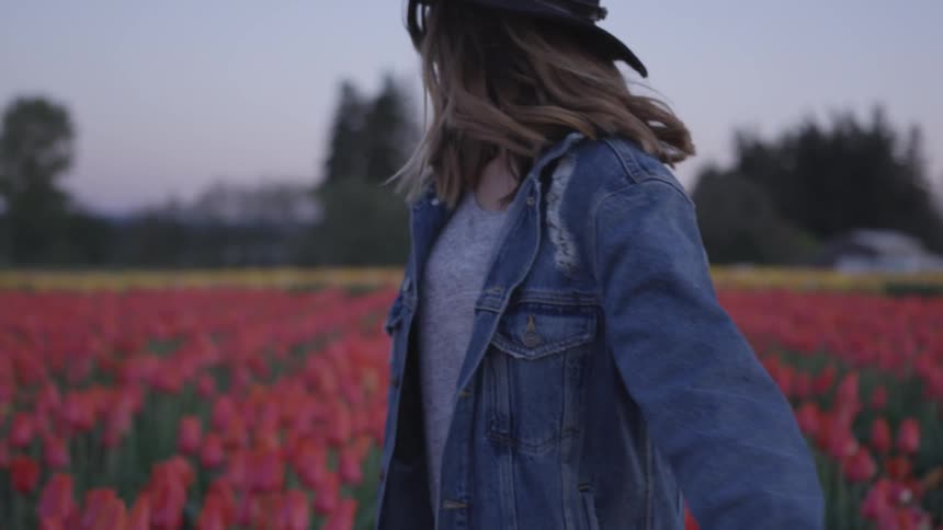 A woman walking through a field of tulips