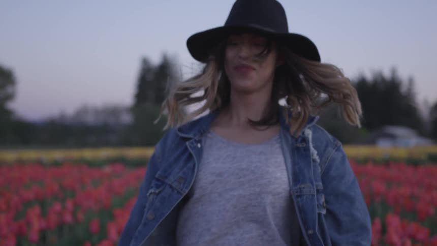Young woman spins around in a field of tulips