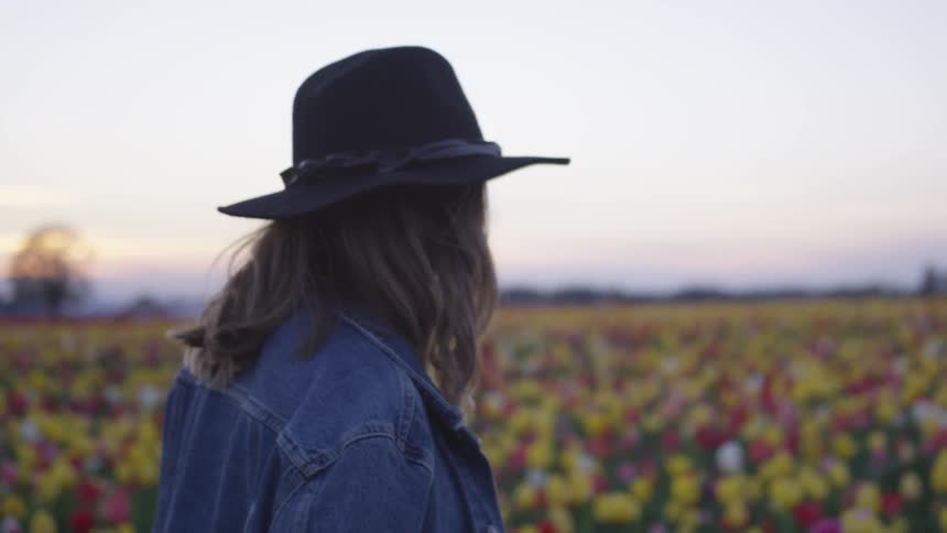 A woman walks through many flowers