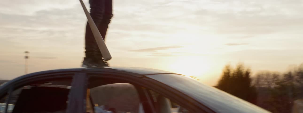 Boy walking on cars holding a bat
