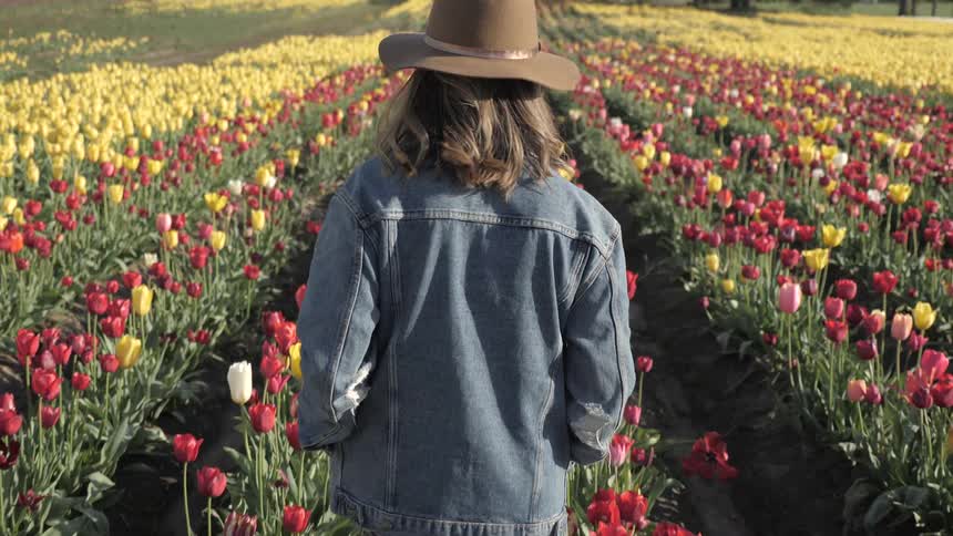 A woman walks through a field of flowers