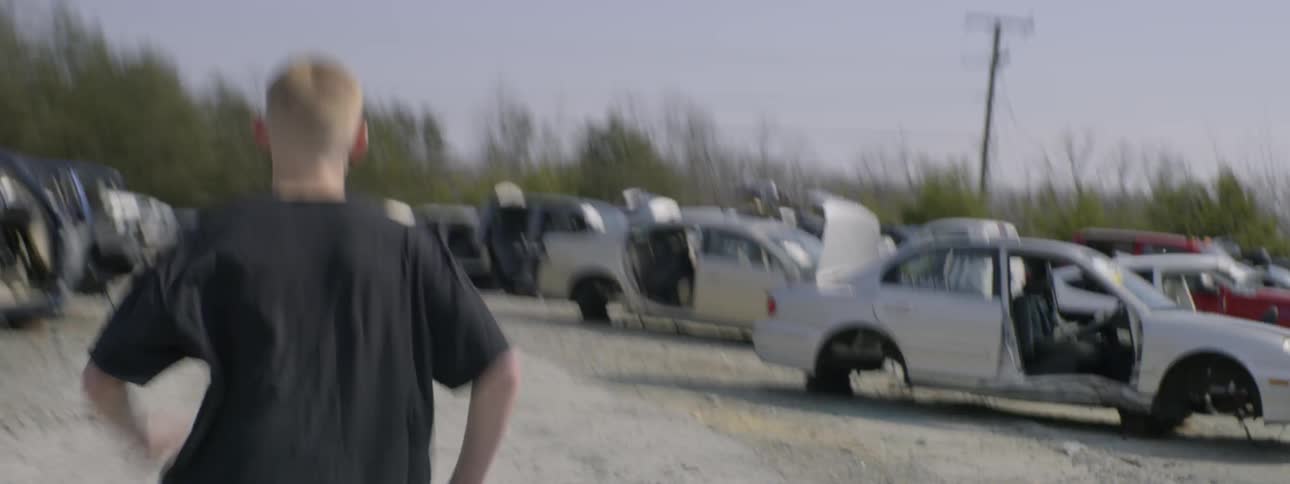 A young boy runs in a junkyard