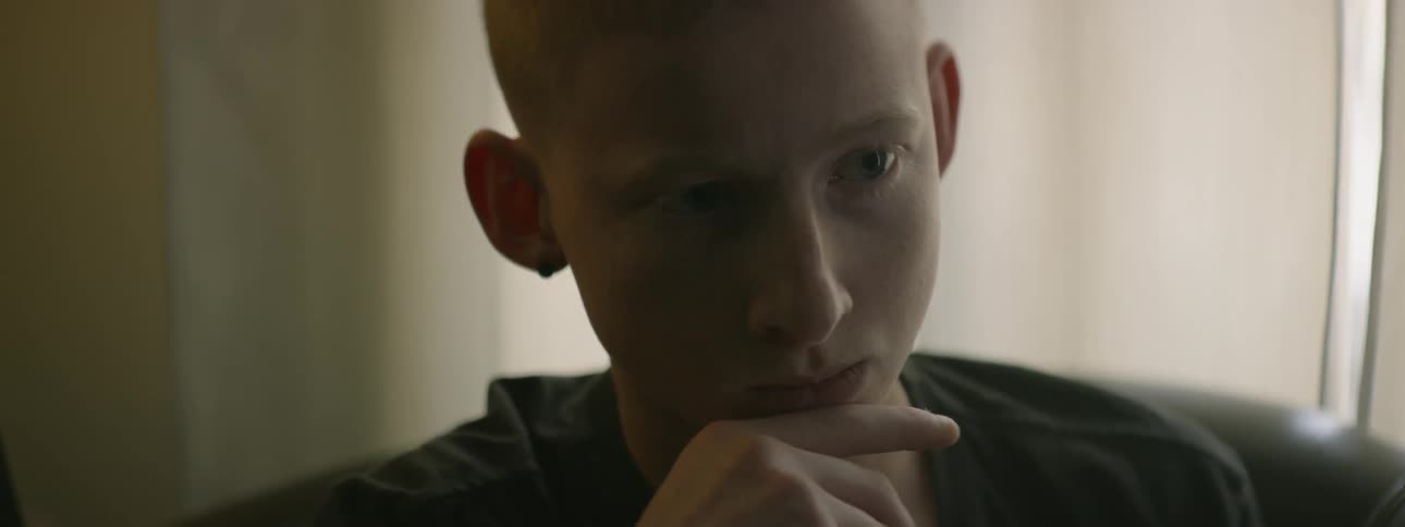 A young white man rubs his chin as he thinks