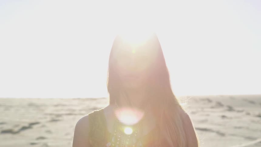 Woman stands near sand under glaring sun