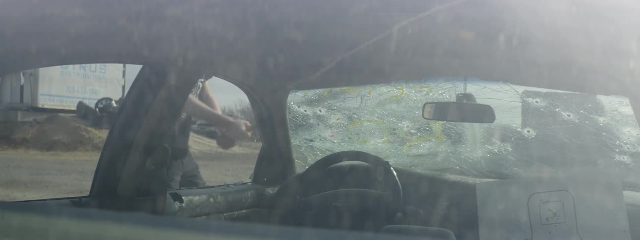 A man with a baseball bat bashing a cars windshield
