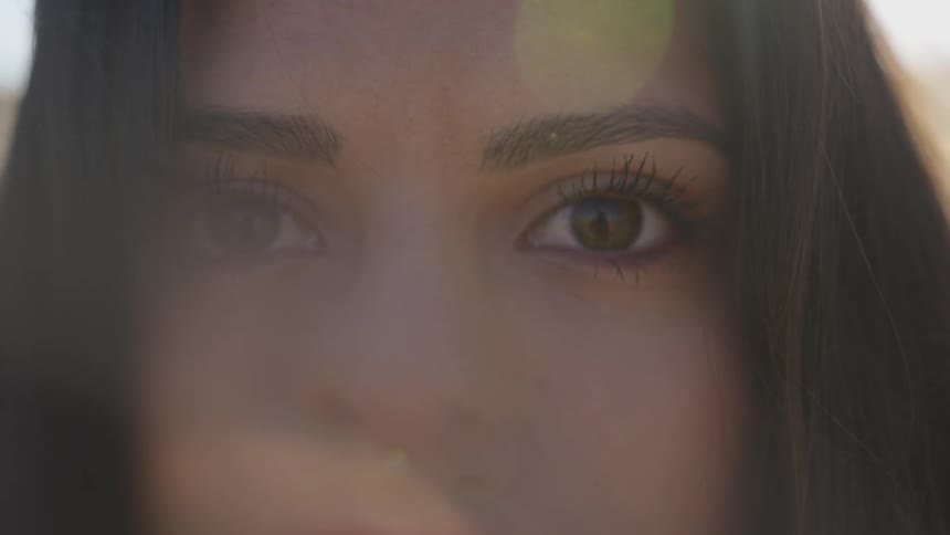 A woman stares into the camera outside on a sunny day