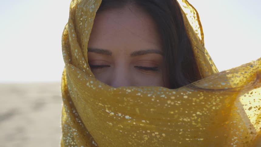 A woman looks into the camera with a scarf covering her face
