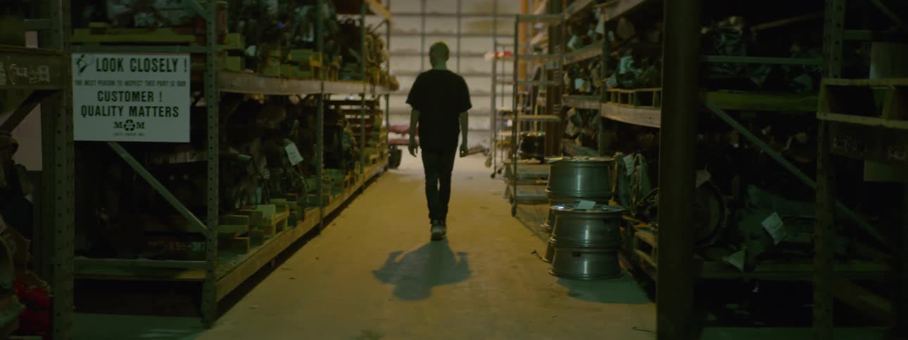 Man walking between the aisles of a heavy equipment shop on a warehouse