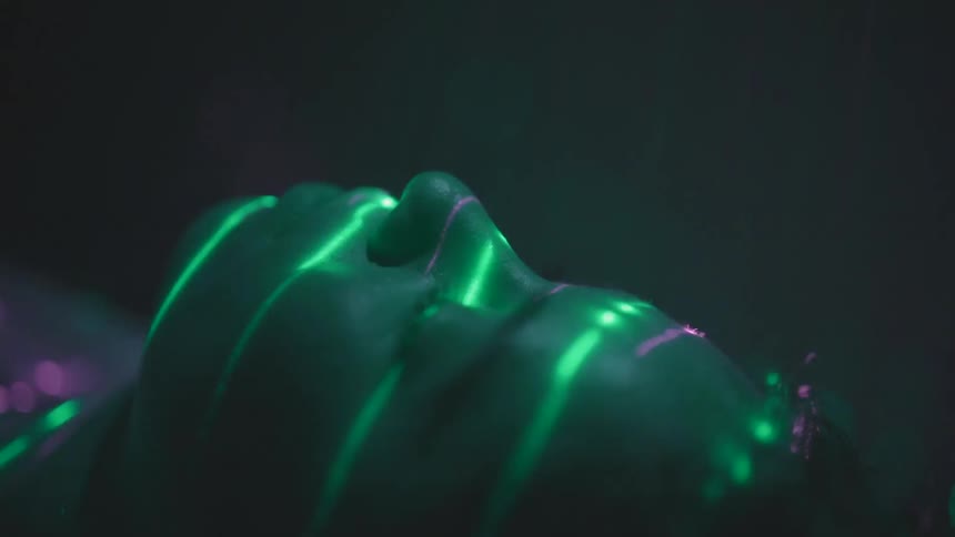 A woman with her eyes closed is scanned by laser light