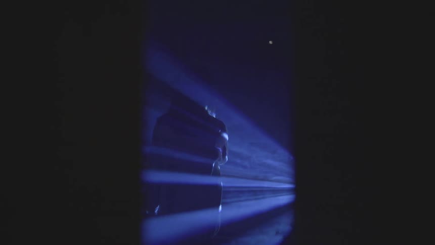A person stand outside in purple light waving their arms