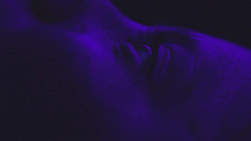 Woman opening her eyes with a purple light reflection on her face