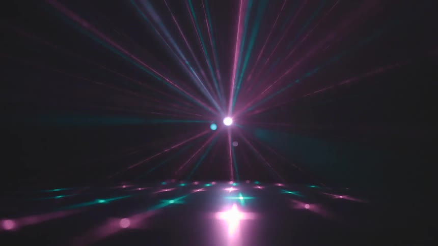 A purple and green light strobes in a dark room