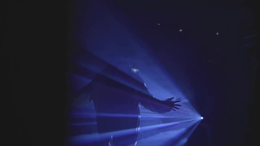Man stands in a concert light and waves his hands