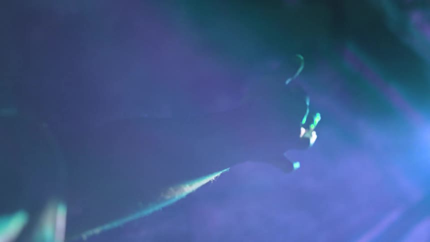 Hand moves through fog in dark room in front of light beams