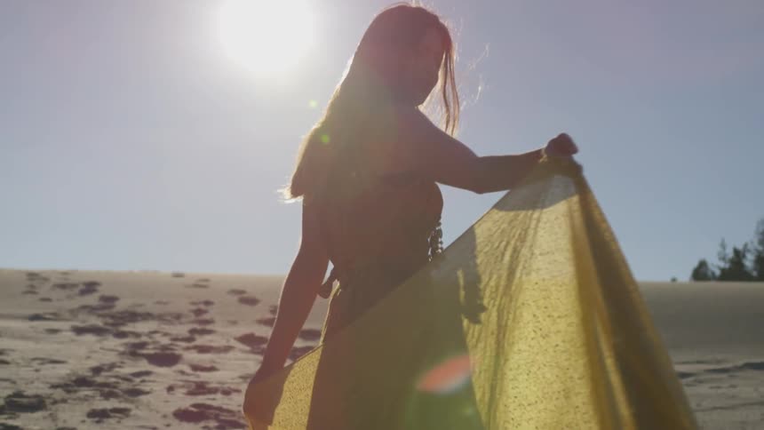 Woman stands in desert with yellow shawl