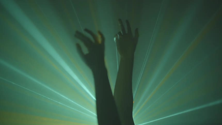 A person waving their arms in front of a laser at a concert