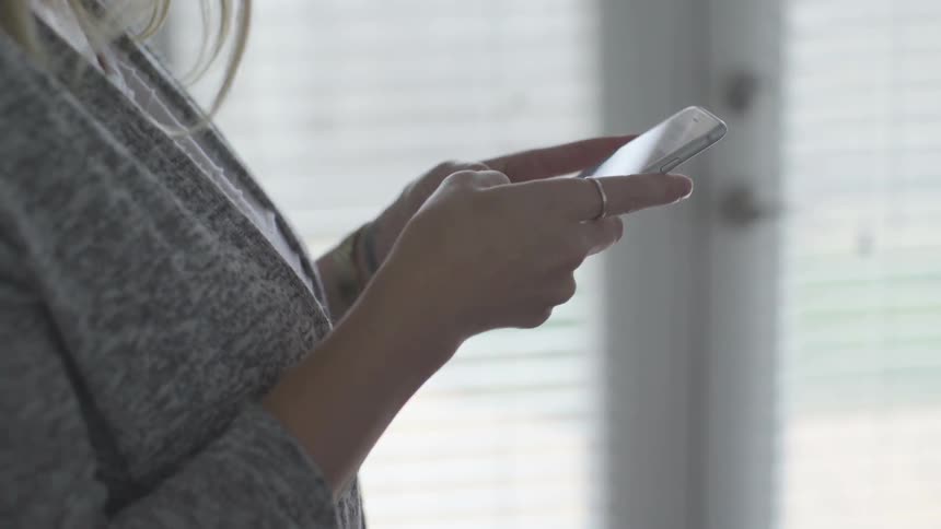 Woman on a room typing on a smartphone