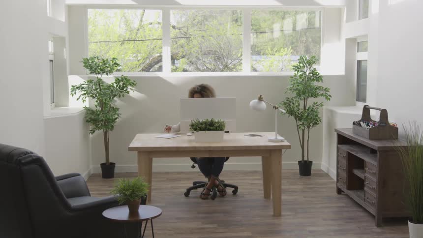 Woman working in an office sitting behind a computer next to a window