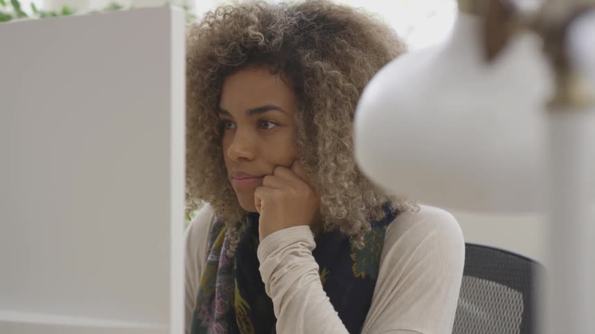Kinky hair hispanic girl looks at desktop computer and smiles indoors