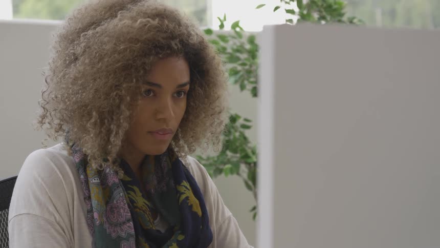 Woman sits at a desk looking at a monitor