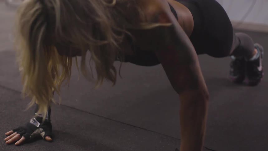 A fit white woman does push ups at the gym