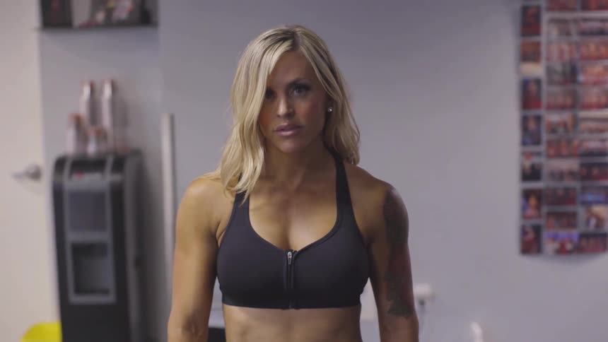 A woman in a sports bra looks into the camera