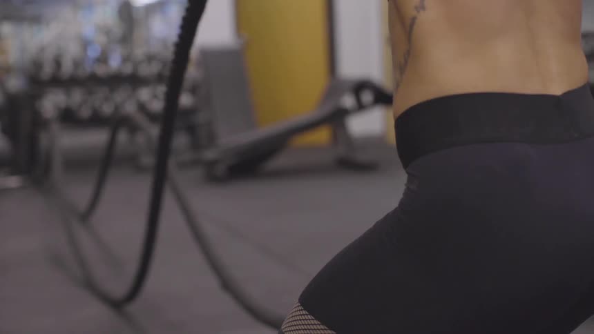 Female working out with battles ropes at the gym