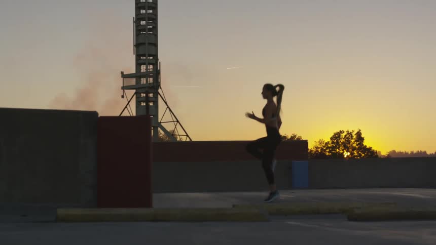 Silhouette of female doing a high knees working out at sunset