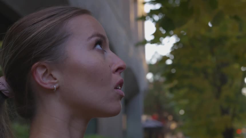 Woman stands outside looking up